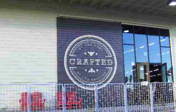 Front door of CRAFTED at the Port of L.A. with its round sign and orange chairs on the porch