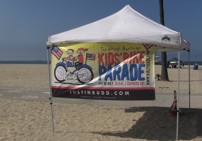 Kids' Bike Parade banner on tent at the beach