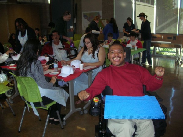 Michael Seale Jr. smiles from his wheelchair in front of an exhibition of his at