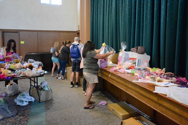 Volunteers pack Easter baskets at a table at the side of a room