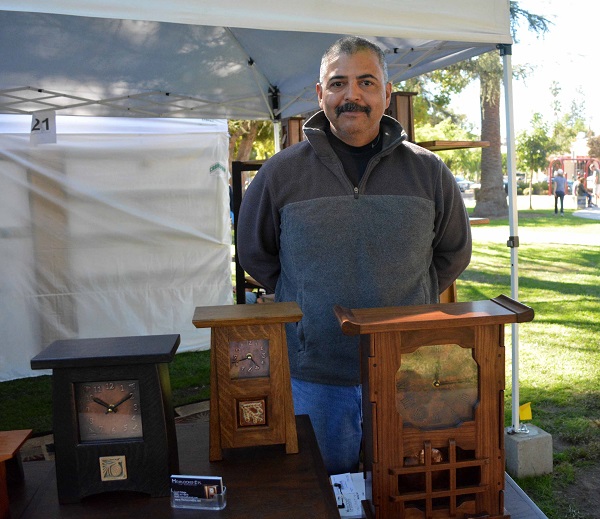 David stands behind three of his clocks in his booth at Pasadena Jackalope Fair