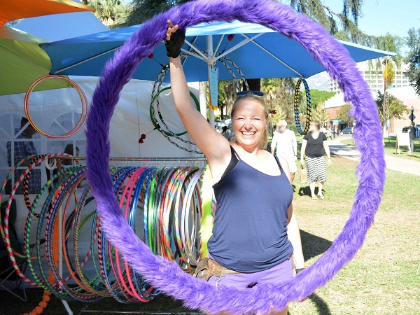 Artisan Jennifer Jensen smiles from within a purple hula hoop covered with fake fun