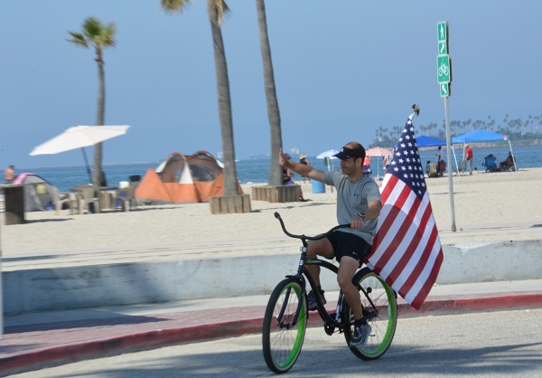 bicyclist with giant flag at the beach