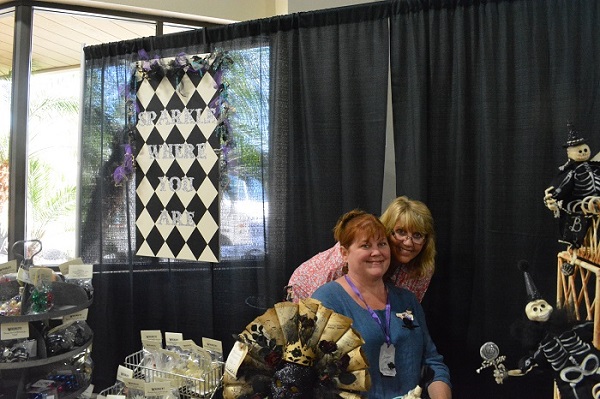 Sisters and Glitterfest founders Sheryl Simpson and Dianne white at check-in table with black-and-white diamond banner