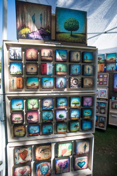 A wooden rack of thirty-six wooden art print miniatures at the Jackalope Fair