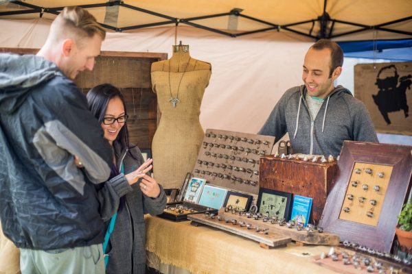Visitors inspect jewelry made from vintage keys at The Key Historic booth during the Pasdena Jackalope Fair.