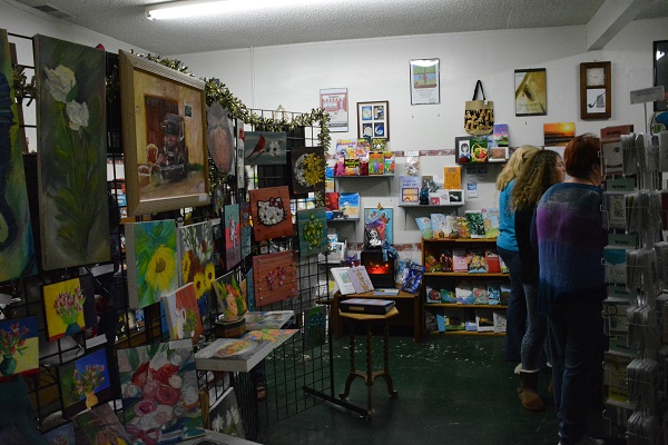 art display and ccustomers inside Pipe & Thimble Bookstore during Winter Wonderland Art Gallery