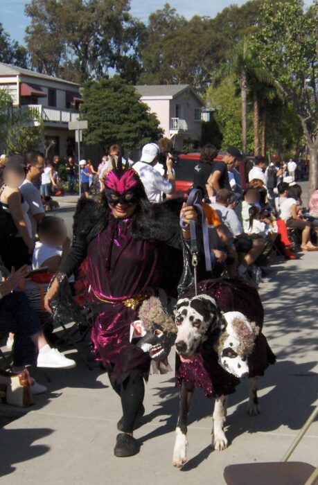 Woman in pink-and-black costume walks dog dressed as a monster