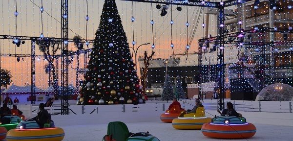 People in ice bumper boats near Christmas tree at sunset
