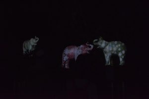Cement elephants on which light patterns of polka dots and stripes are being projected at LA Zoo Lights