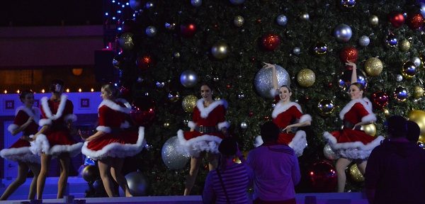 five women in red fake-fur Santa suits sing and dance