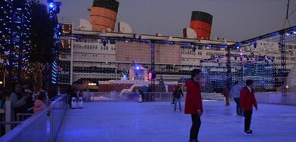 skaters on small square rink with Queen Mary in the background