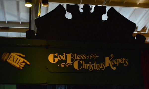 Green "God bless the Christmas Keeprs" sign with gold lettering