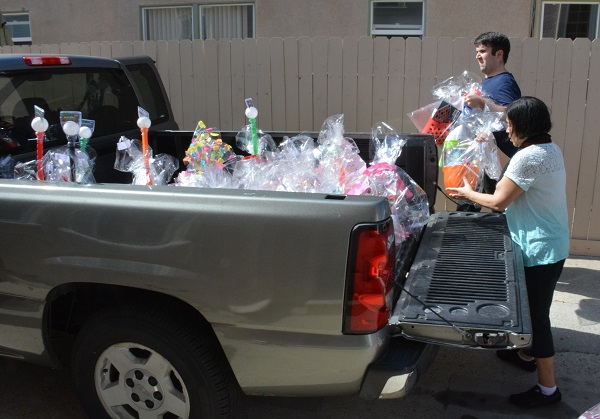 Volunteers load completed Easter baskets into a flatbed of a gray pickup truck