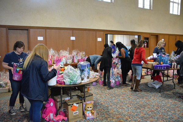 Volunteers put supplies into Easter baskets at two tables in the church hall