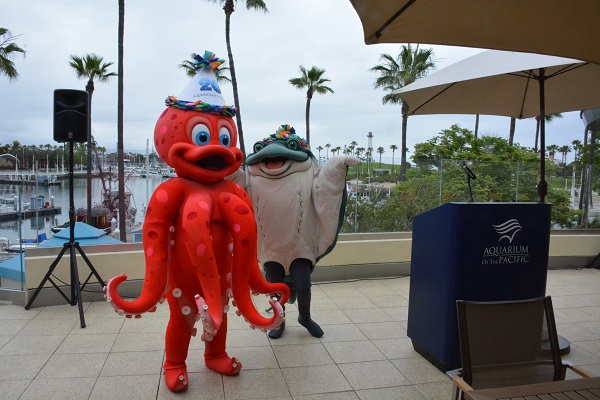Aquarium of the Pacific costumed stingray and octopus mascots with "20-year" anniversary party hats on Aquarium of the Pacifi's outdoor terrace