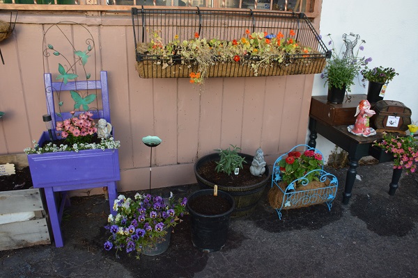 flowers in a windowbox and in a purple cart outside the store