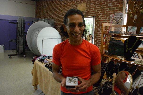 Artist Carlos Boisselle displays a sterling silver dolphin necklace on a chaing at SPAA Spring Craft Faire