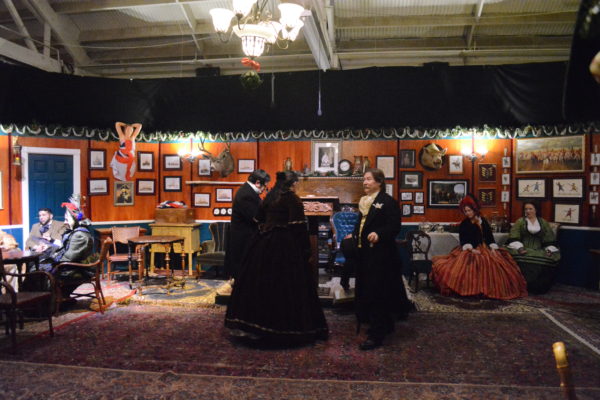 People in Victorian dress chat in Adventurers Club parlor