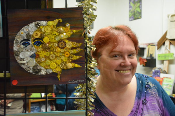 Artist Carol Newell poses next to her "Sun and Moon" button art piece