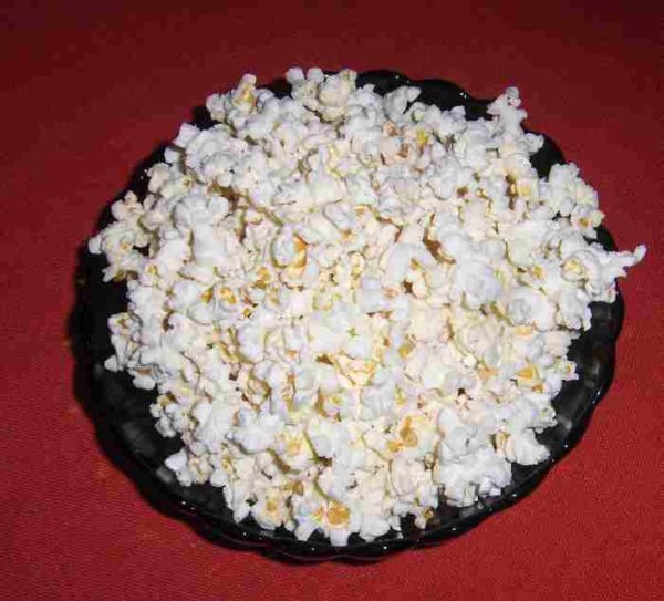 white popcorn overflows a green bowl on a red tablecloth
