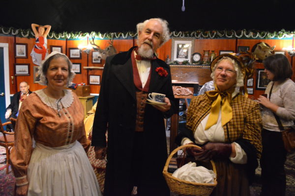 Robert Young, as Charles Dickens, flanked by two women in Victorian dress
