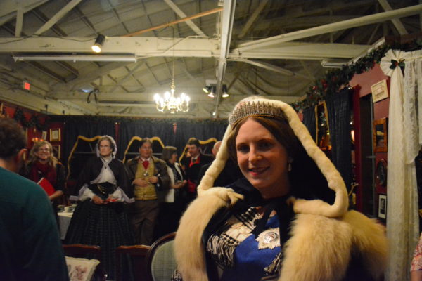 Laurie Tavan, as Queen Victoria, smiles from under a fur-trimmed hooded cape