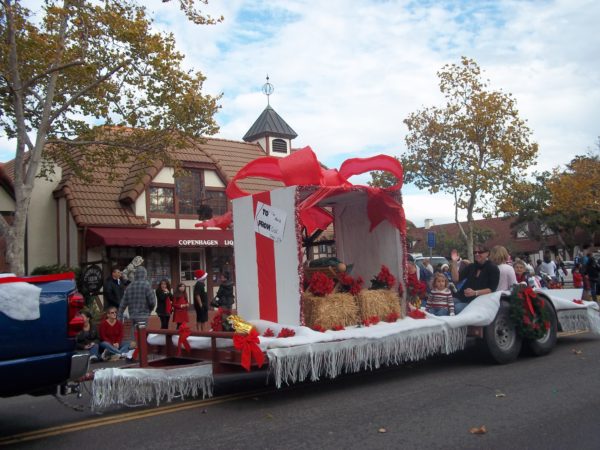 Julefest parae float decorated to look like a Christmas package with red poinsettias goes by as spectators watch