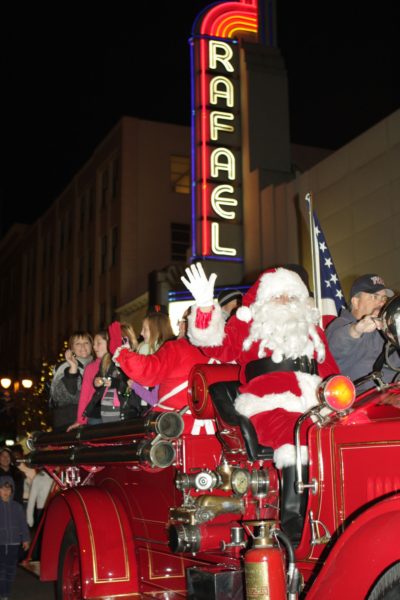 Santa waves from a firetruck as he goes past a movie marquee in San Rafael Parade of Lights