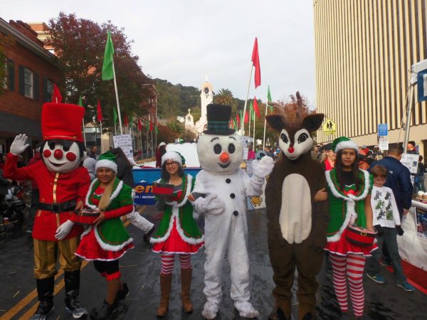 Parade with snowman, reindeer and toy solider characters in costume on San Rafael street