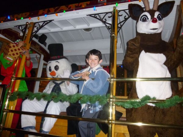 Child rides a trolley with costumed reindeer and snowman characters
