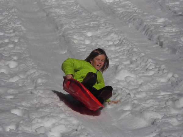 Girl sleds down a hill on a red sled