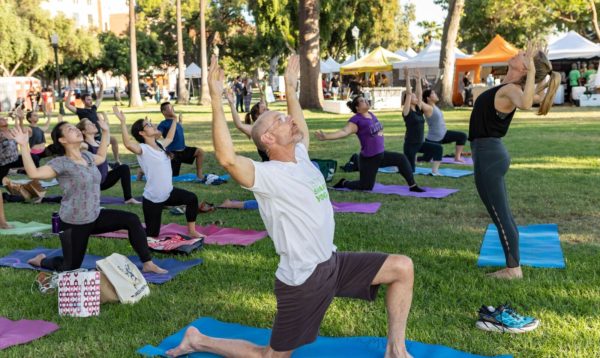 Man leads a group in yoga stretches in Central Park, Pasadena.