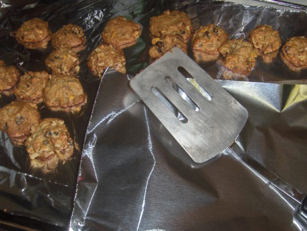 Spatula and foil next to a dozen freshly-baked cookies set out to cool