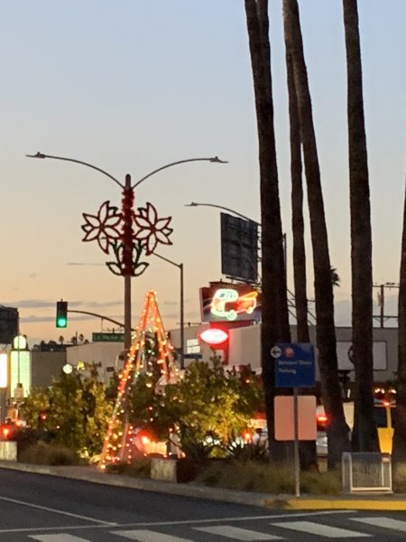 Poinsettia adorns streetlamp as Christmas tree made of lights glows at sunset
