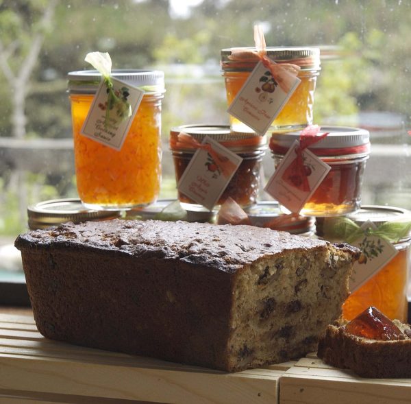 Jars of amber handcrafted honey sit next to a walnut cake