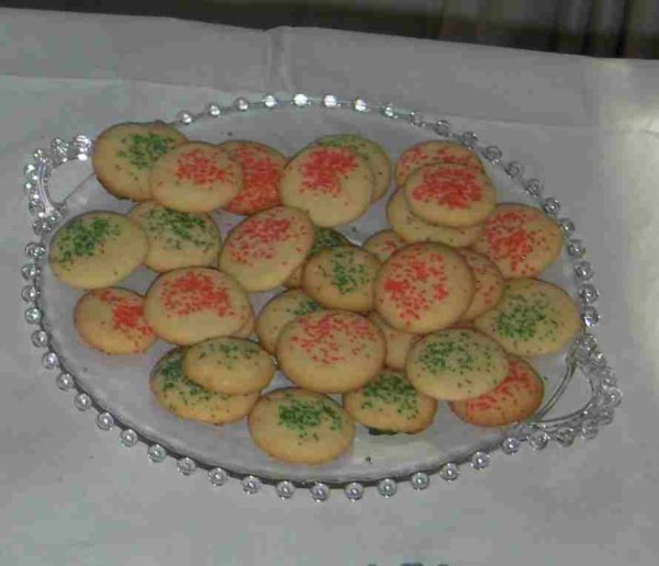 Sugar cookies with red and green sprinkles arranged on clear-glass Candlewick dessert plate