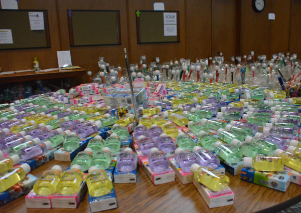 Bottles of multicolored shampoo arranged on a table with filled Easter baskets in the background at church fellowship hall