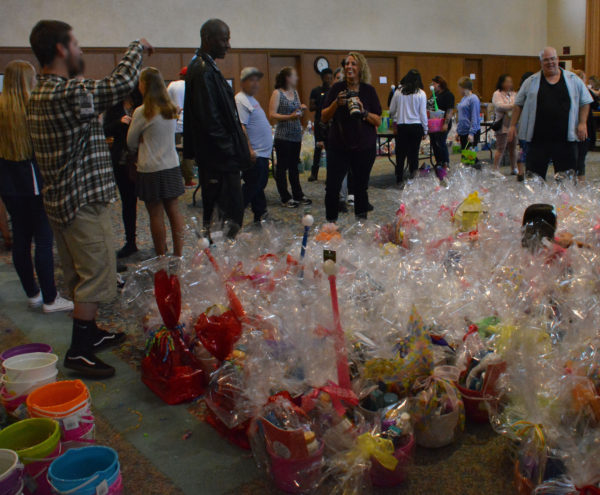 bearded man photographs finished baskets as Jim "Woody" Woodson and community members smile from fellowship hall