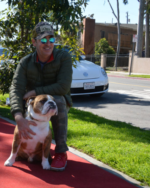 Ralph smiles as he poses with bulldog "POTUS", on the red carpet.