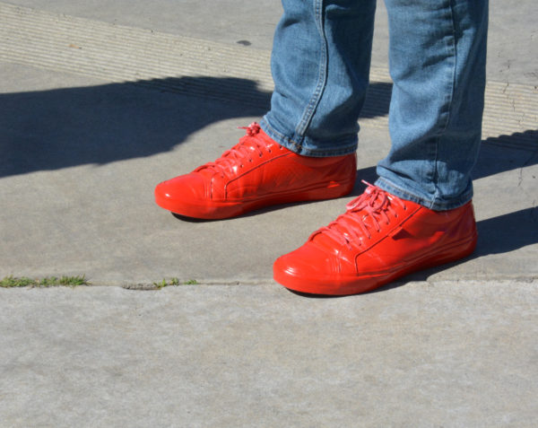 bluejeaned legs ending in red spraypainted athletic shoes