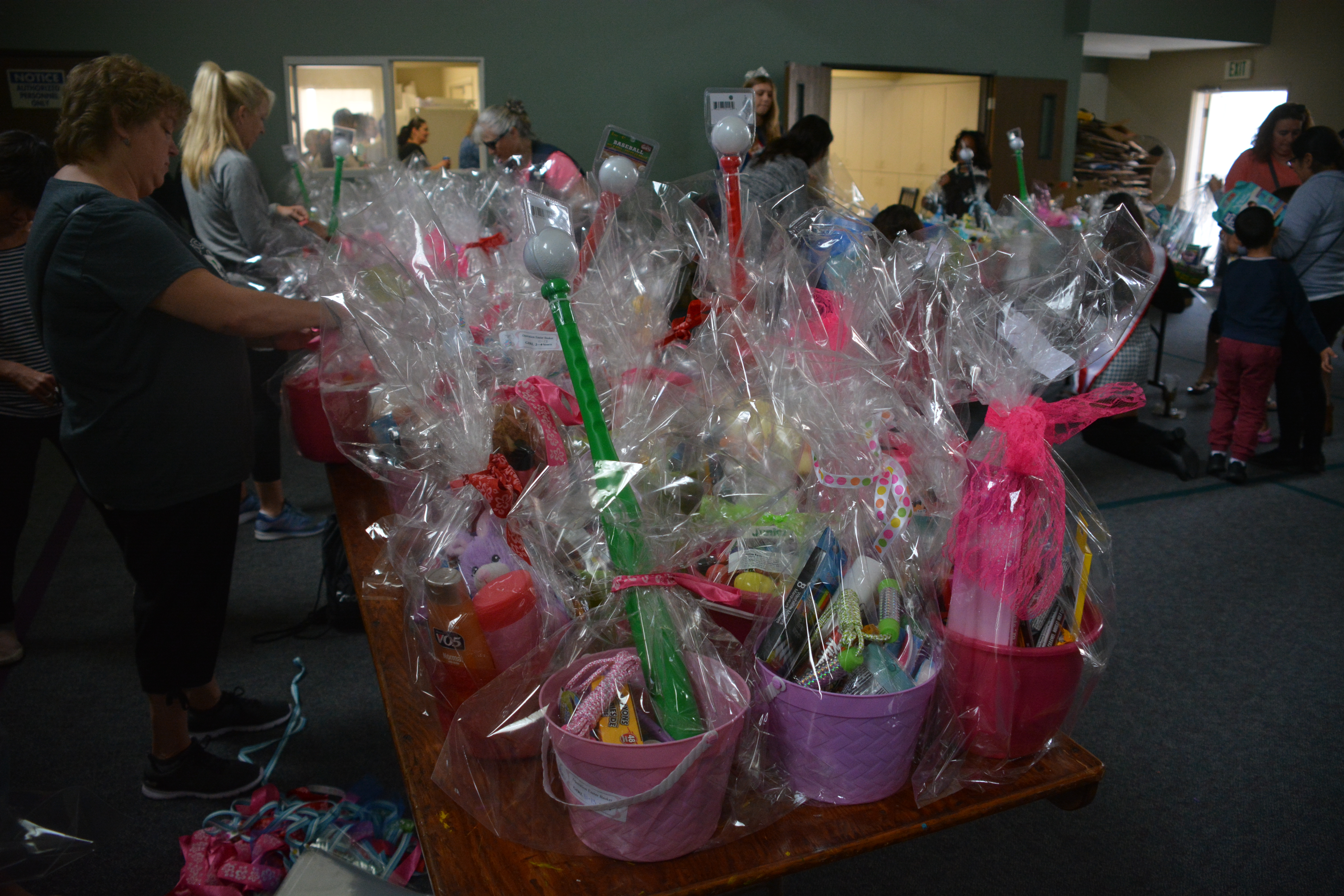 Women tie ribbons on Easter baskets at Operation Easter Basket