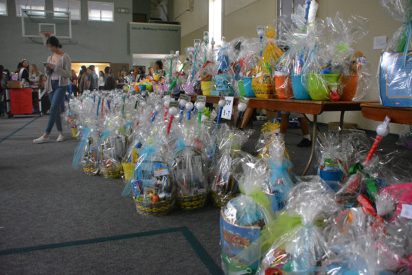 Long shot of comnpleted Easter baskets on floor of Community Center as volunteer texts