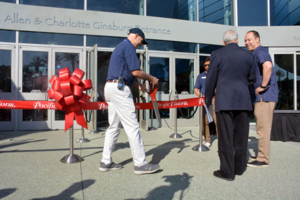 Aquarium of the Pacific Festival Organizer Peter Martineau approaches Dr. Schubel to offer him a giant pair of scissors as the red ribbon stands waiting outside the Aquarium doors
