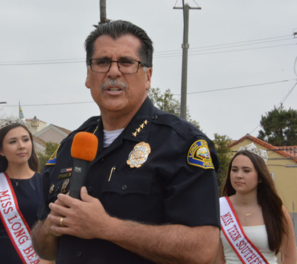 Police Chief Robert Luna speaks on mic, flanked by Miss Long Beach and Miss Teen Southern California