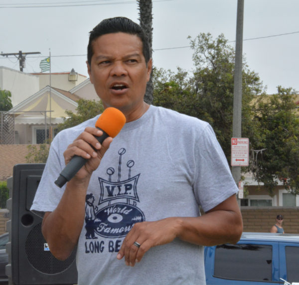 Tony Crtu, wearing a gray "VIP Records Long beach" t-shrit, uses a handheld mic to speak to the crowd