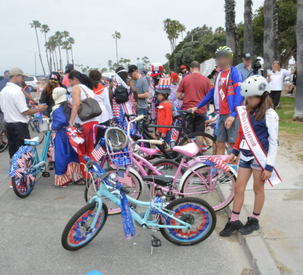 parade attendees with red-white-and-blue decorated bikes wait in the parking lot