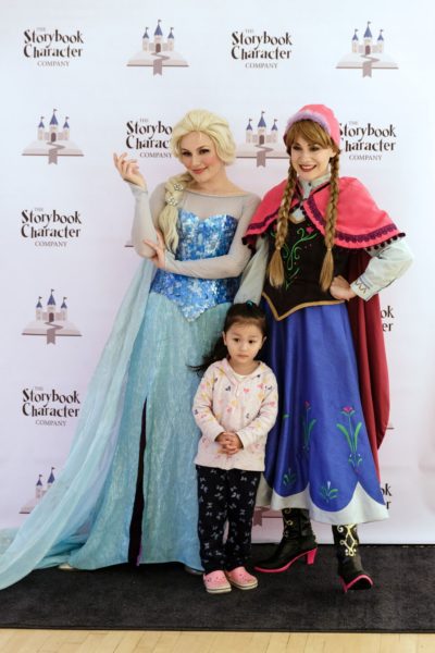 Small girl poses for a picture with "Elsa" from Frozen and Red Riding Hood