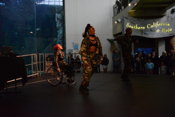 Auti Angel performs hip hop number from her wheelchair with two dancers in fatigues