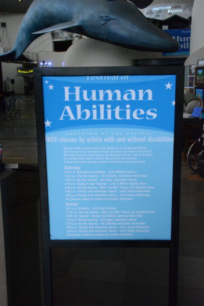 Festival of Human Abilities schedule of performances in Aquarium's Great Hall with huge blue whale sculpture in the background